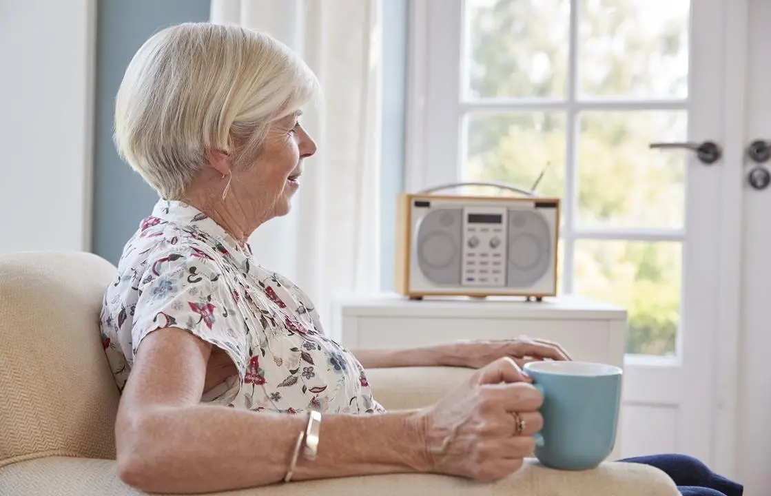Mujer mayor escucha la radio en su casa