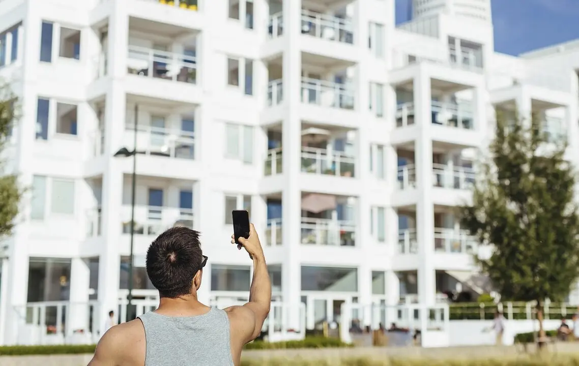 Un hombre fotograf&iacute;a un edificio de viviendas donde hay pisos tur&iacute;sticos