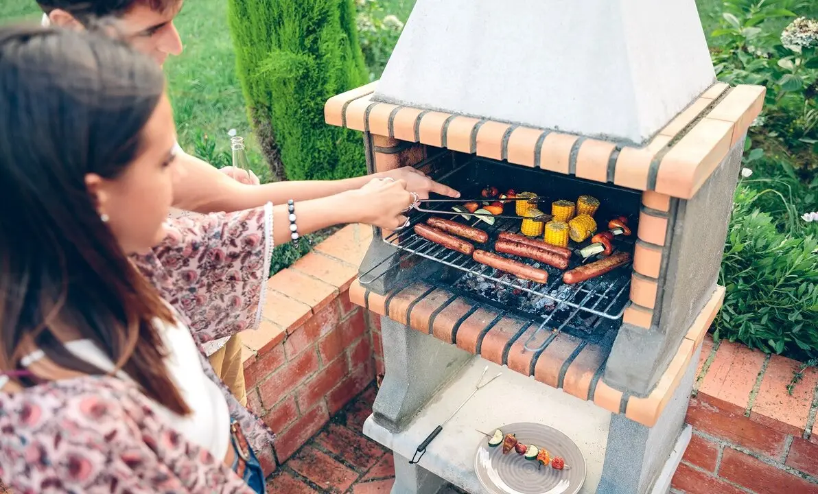 Una pareja disfruta cocinando en una barbacoa de obra