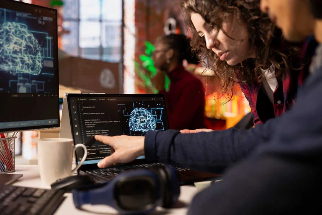 Coworkers doing brainstorming in AI tech agency providing software development services. Close up of startup office colleagues cooperating, using artificial intelligence to streamline coding process