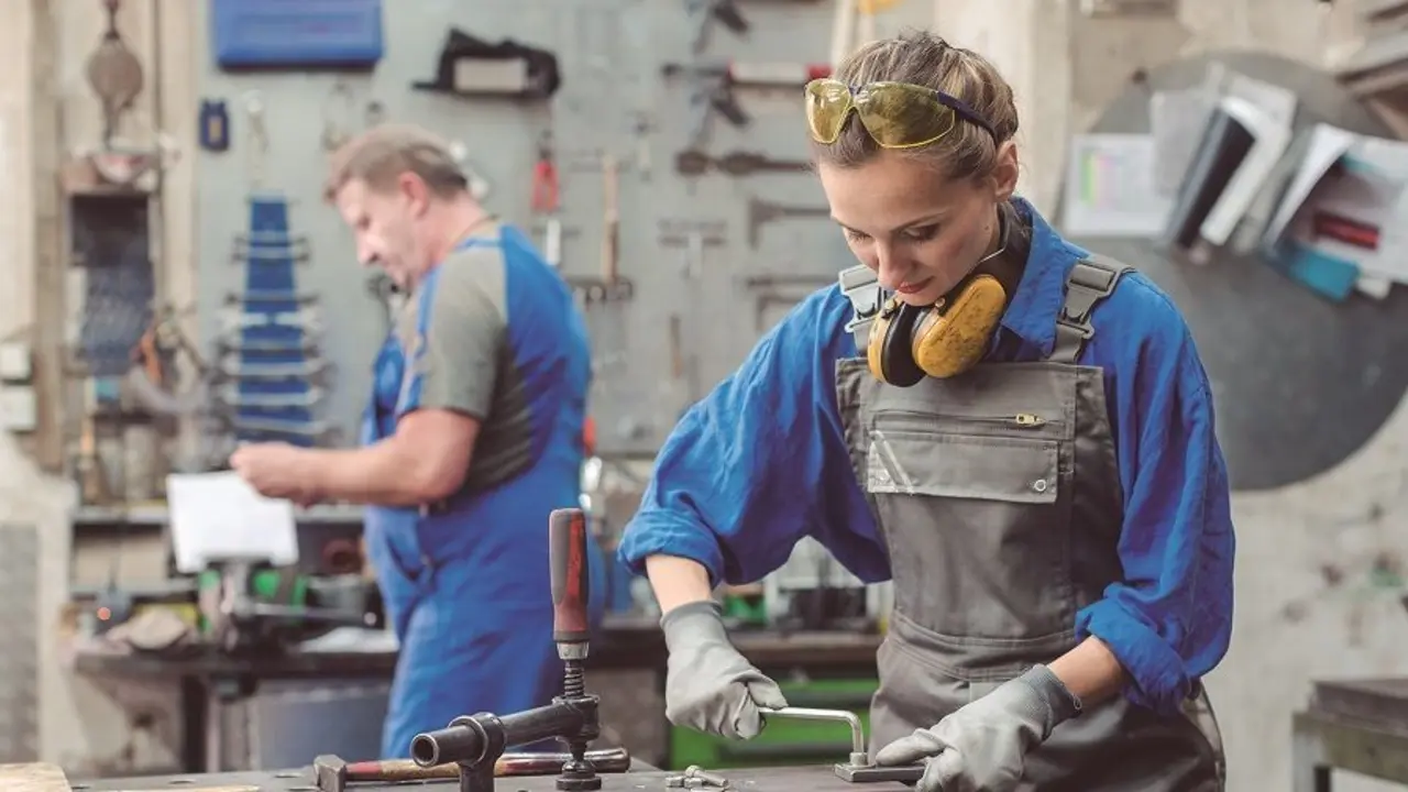 Man and woman working together in metal workshop with their tools