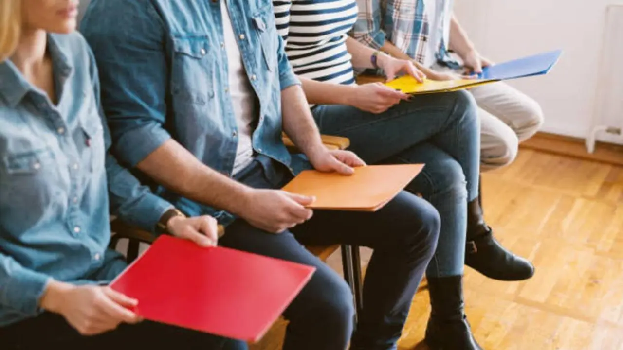 Close up view of young people sitting in chairs with folders before the job interview in the waiting room.