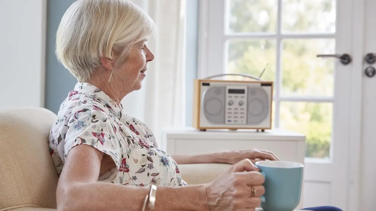 Mujer mayor escucha la radio en su casa