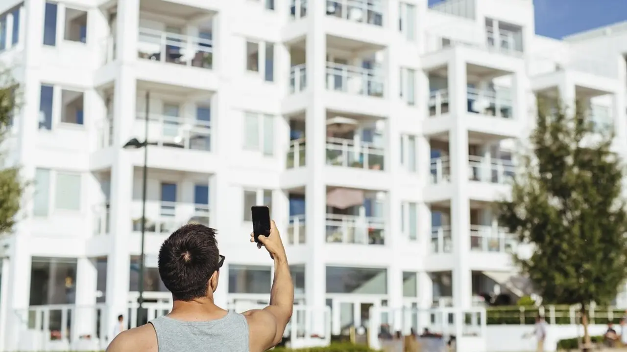 Un hombre fotograf&iacute;a un edificio de viviendas donde hay pisos tur&iacute;sticos