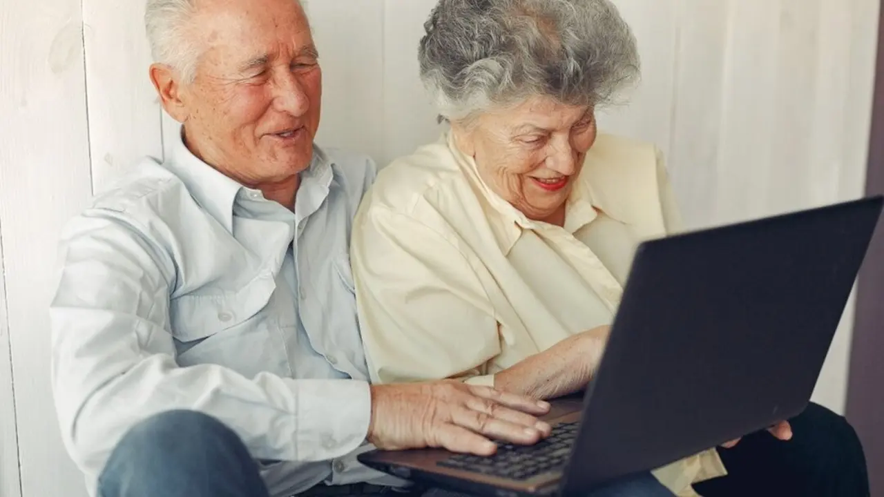Grandparents at home. Old people use the laptop. Senior in a blue shirt.