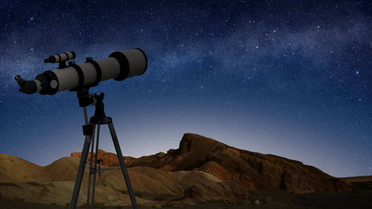 telescope on a tripod pointing at starry night sky