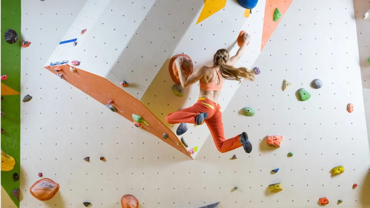 Una mujer hace escalada en un muro de boulder