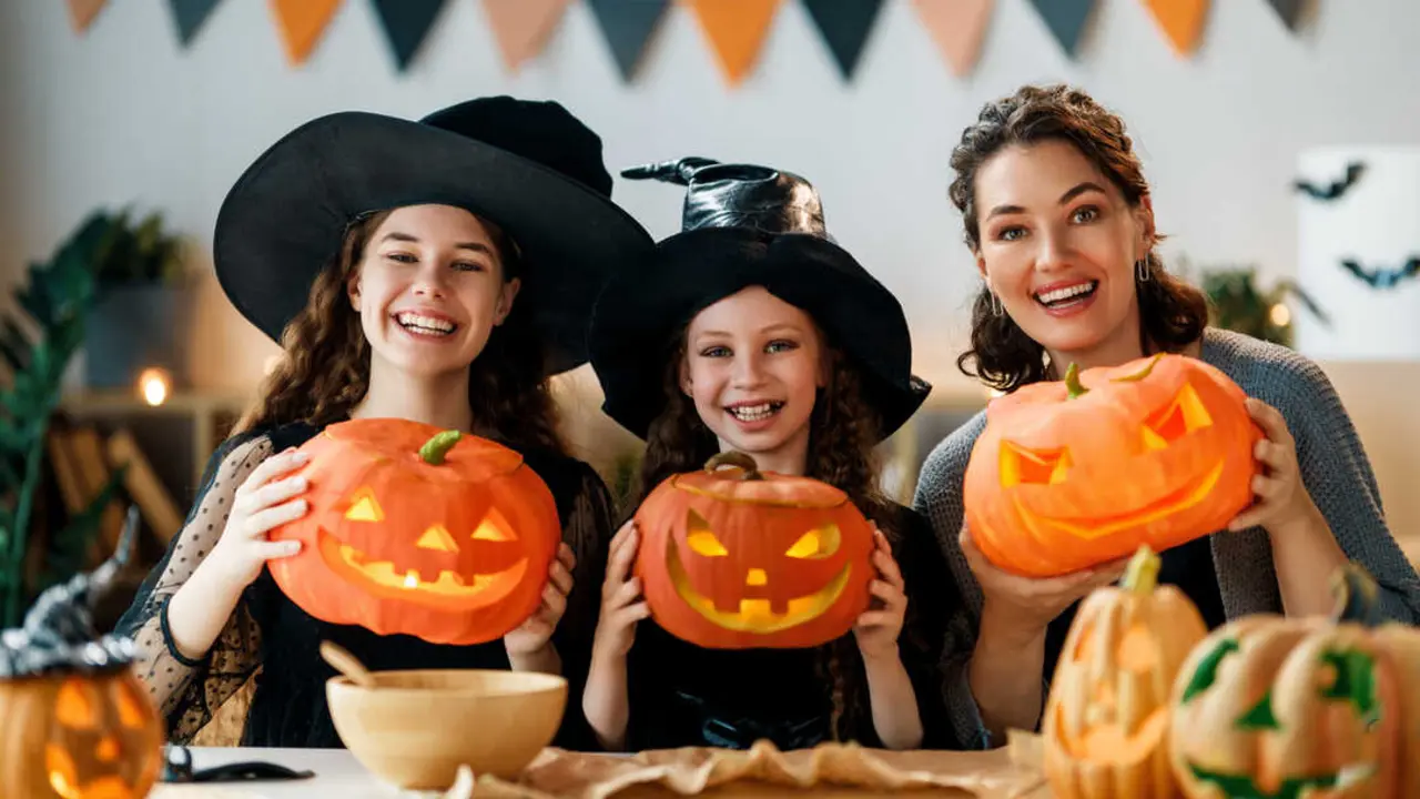 Happy family preparing for Halloween. Mother and children carving pumpkins at home.