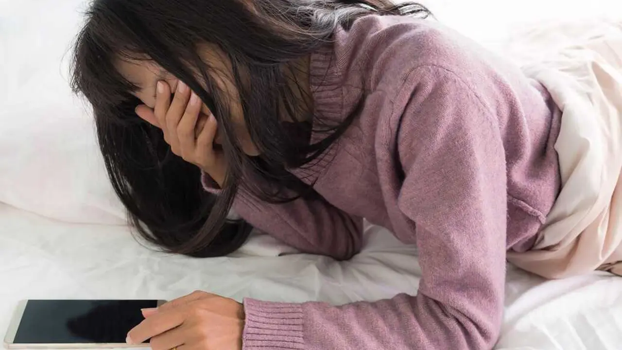 Una mujer v&iacute;ctima de sextorsi&oacute;n a trav&eacute;s de redes sociales mira su tel&eacute;fono m&oacute;vil