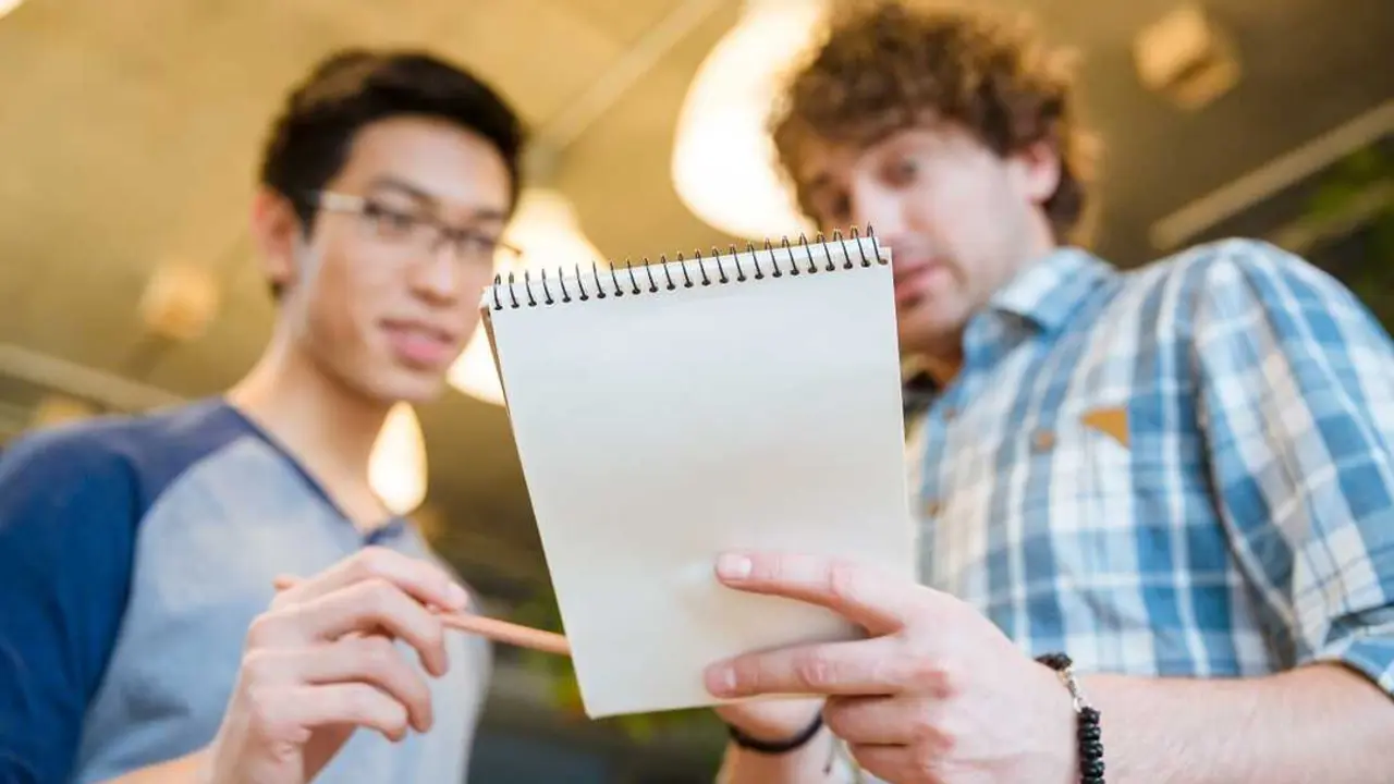 Student showing his notes in notepad to his friend