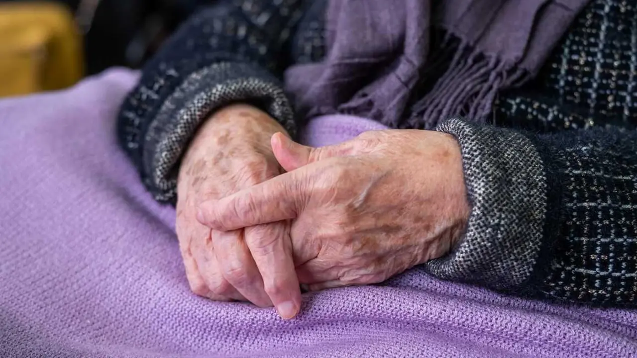 Mujer mayor con manos en el regazo