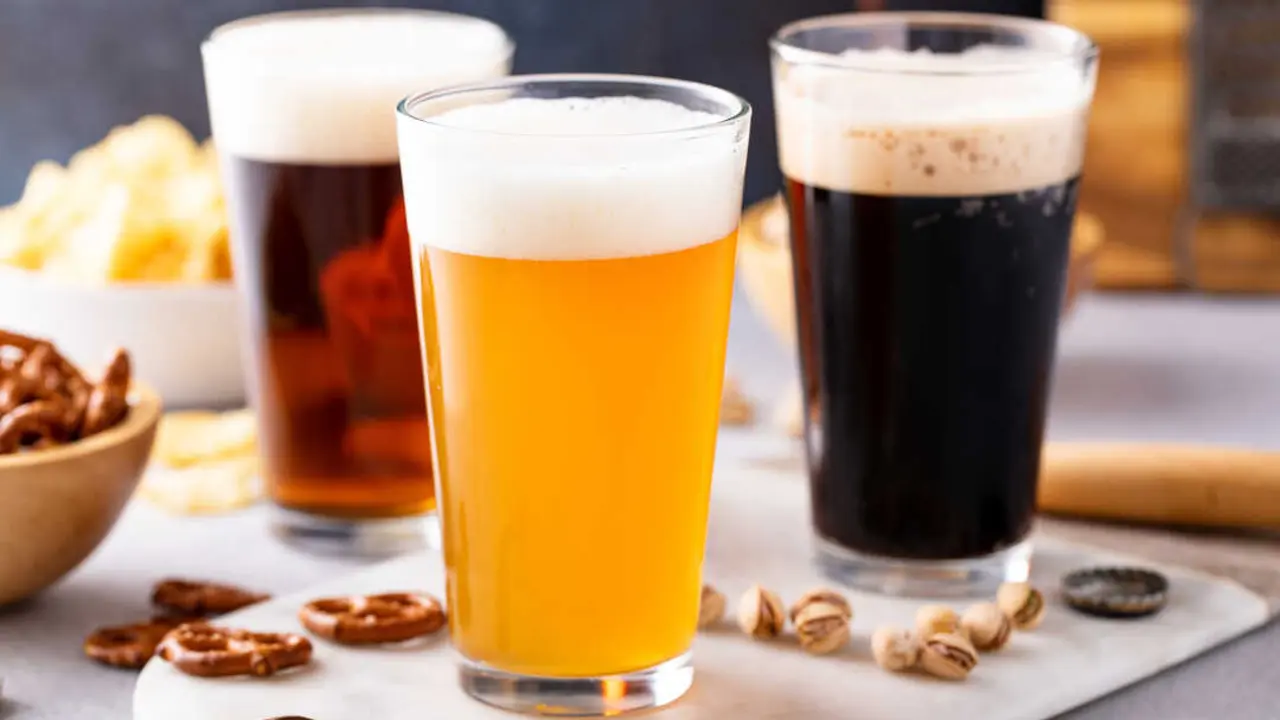 Variety of beer with dark stout, traditional lager and belgian white served with snacks on the table