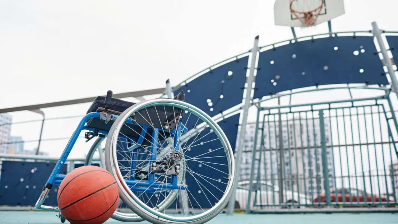 Image of empty wheelchair with basketball ball on the outdoor sport ground