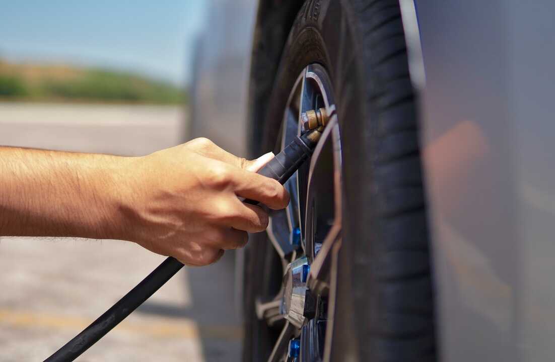 Hombre inflando neumático de coche