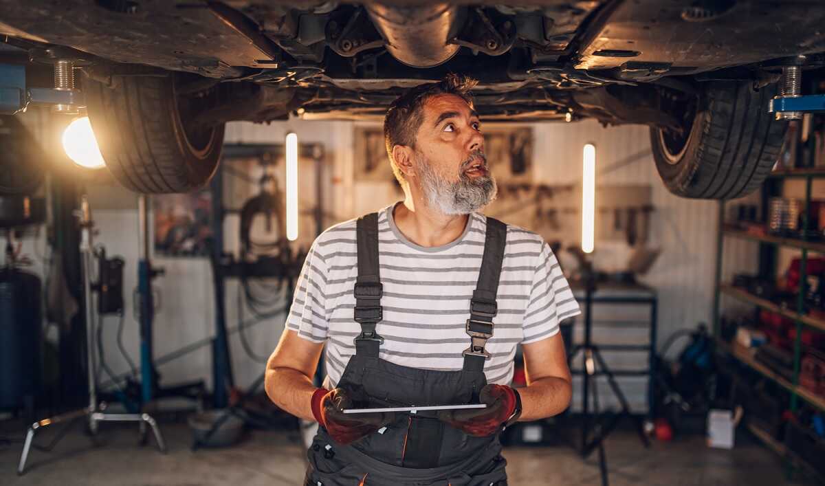 Mecánico inspecciona sistema suspensión de un coche